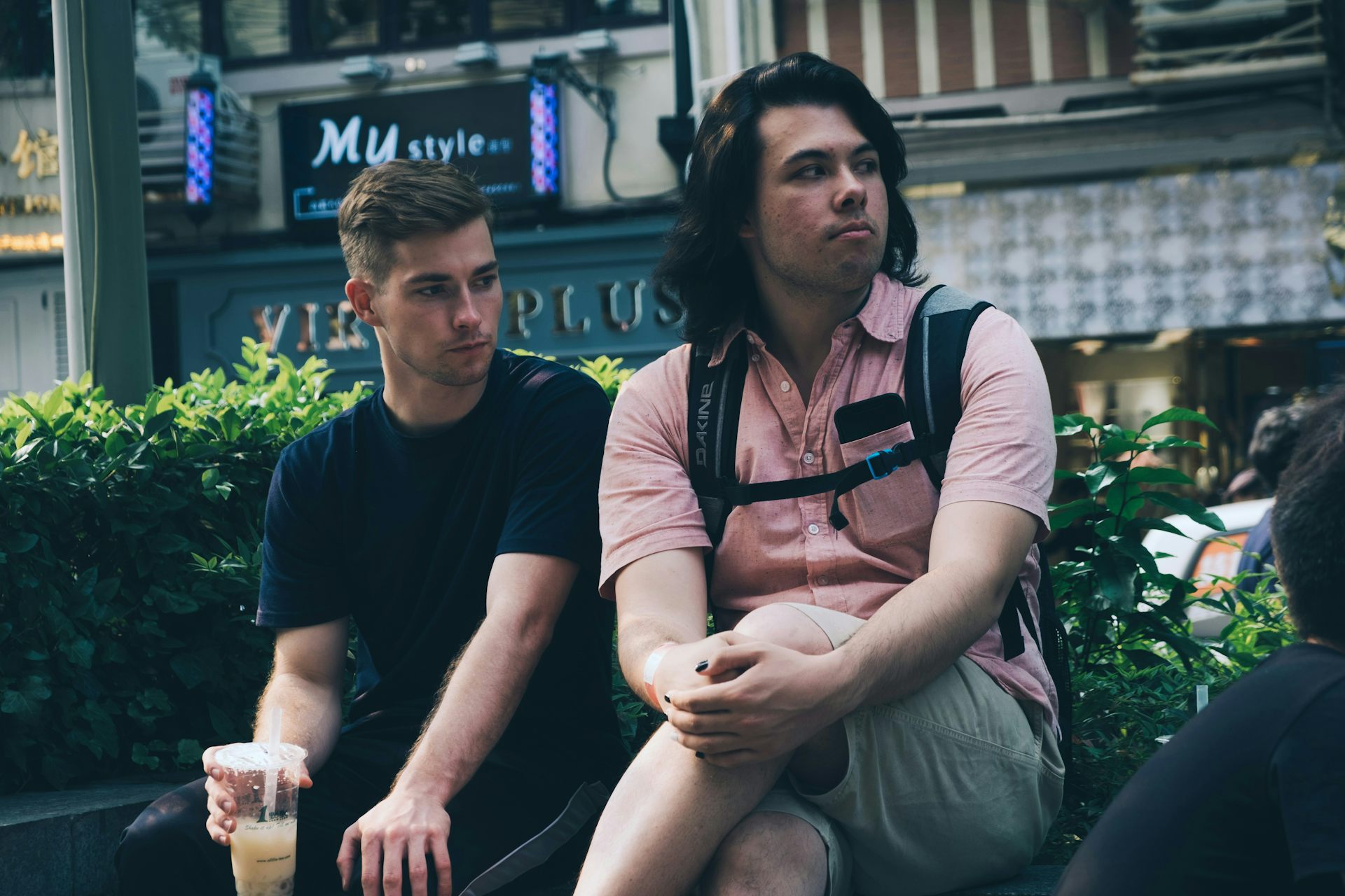 Two young men sitting on a bench. One is looking away from the other