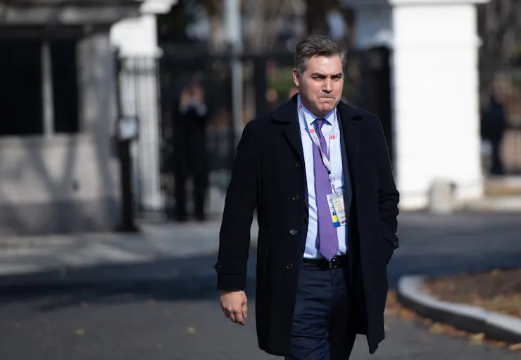 A man in a suit walking near a white building.