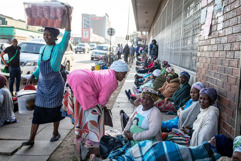 Elderly women sit in a row on a city pavement