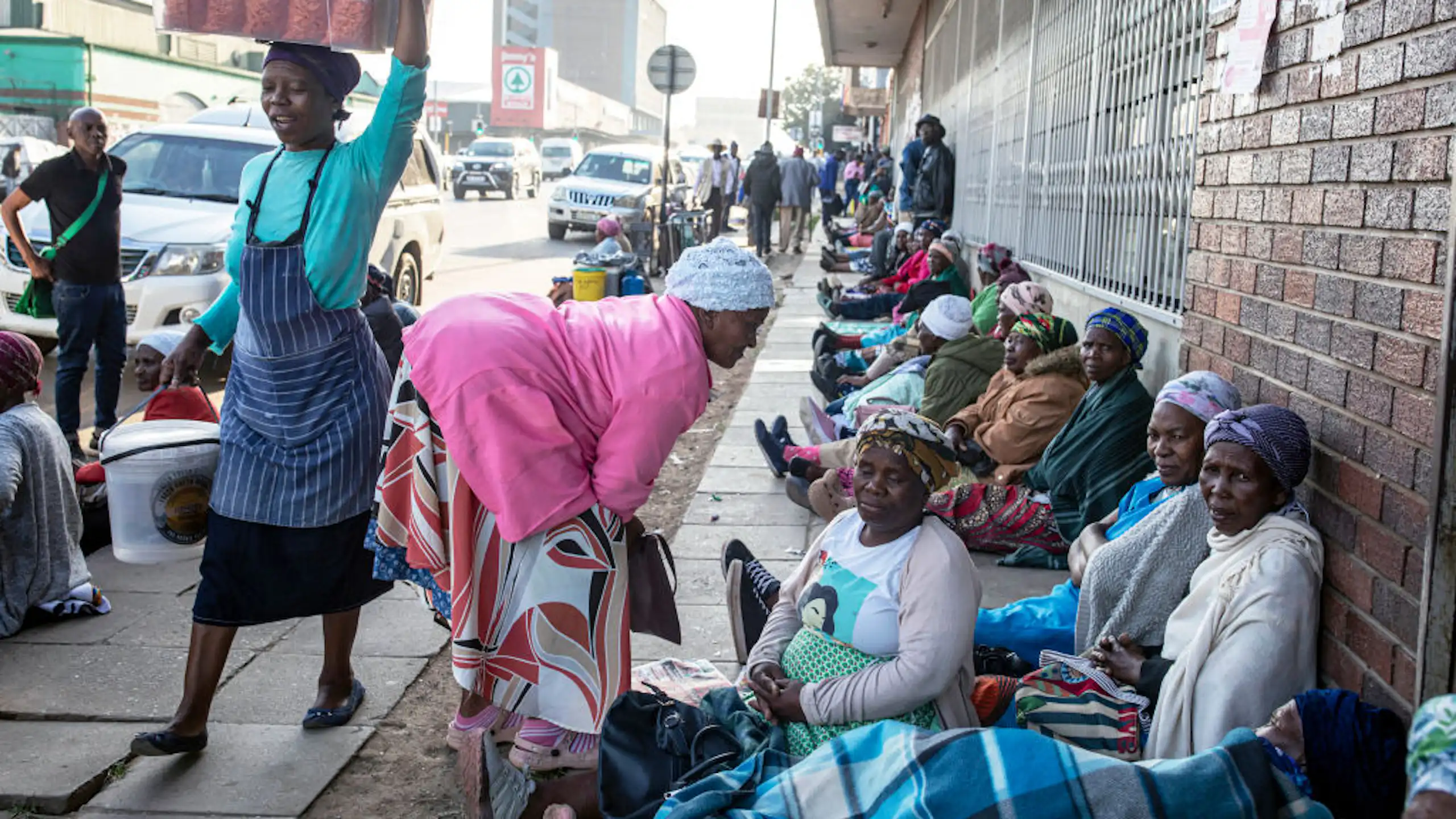 Elderly women sit in a row on a city pavement