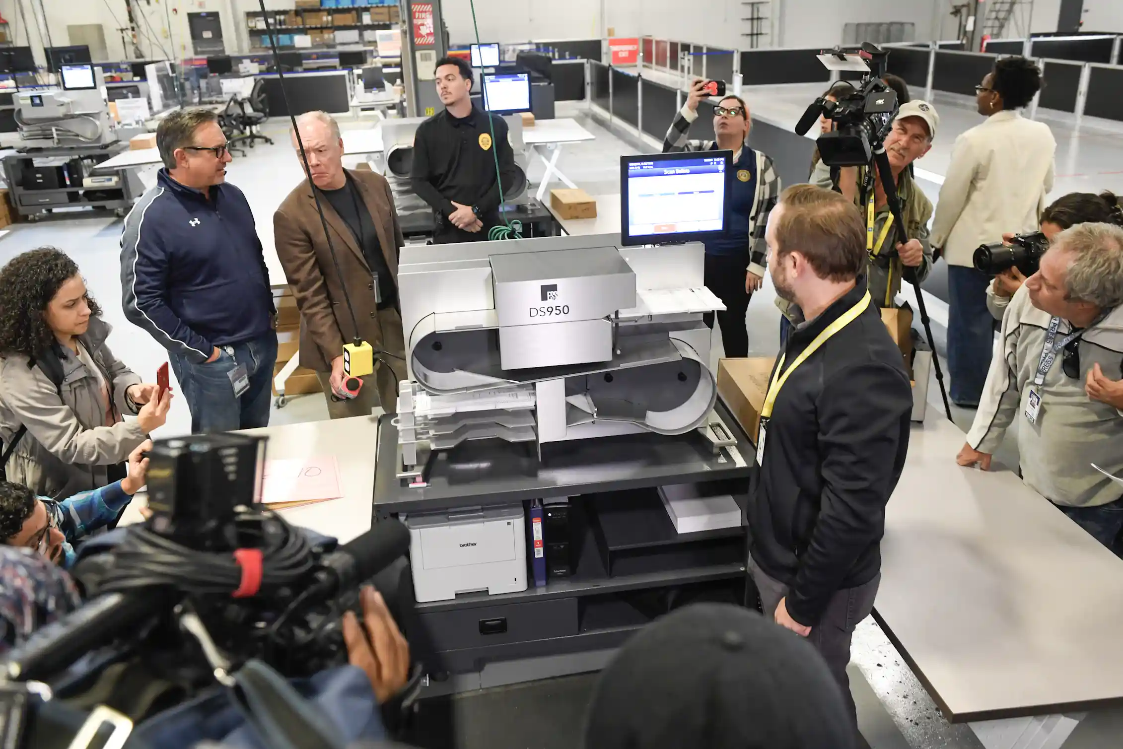 People in a large room standing around a machine.
