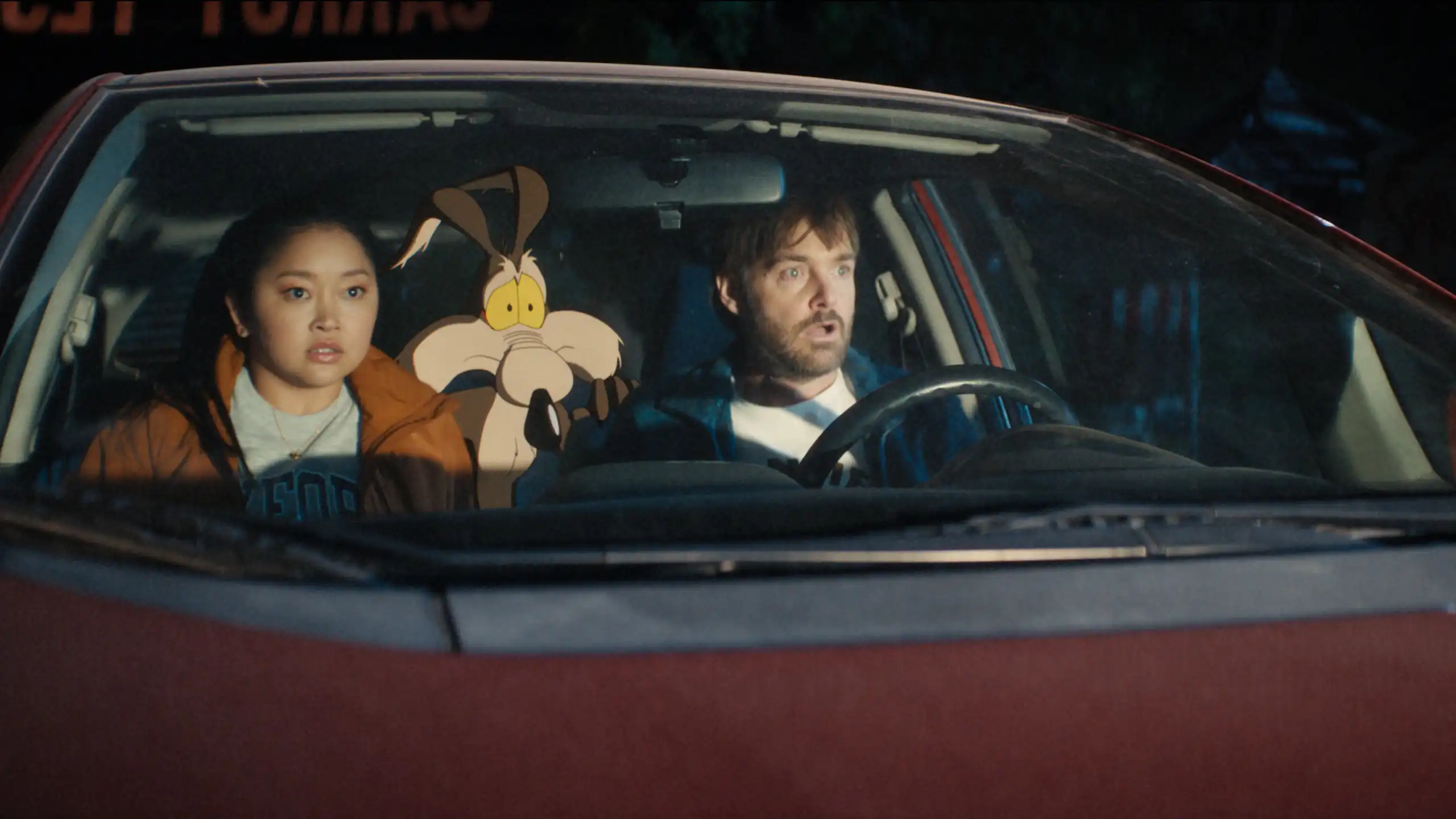 Human actors Lana Condor and Will Forte sit in a car with the animated character Wile E. Coyote in a still from the film Coyote vs. Acme