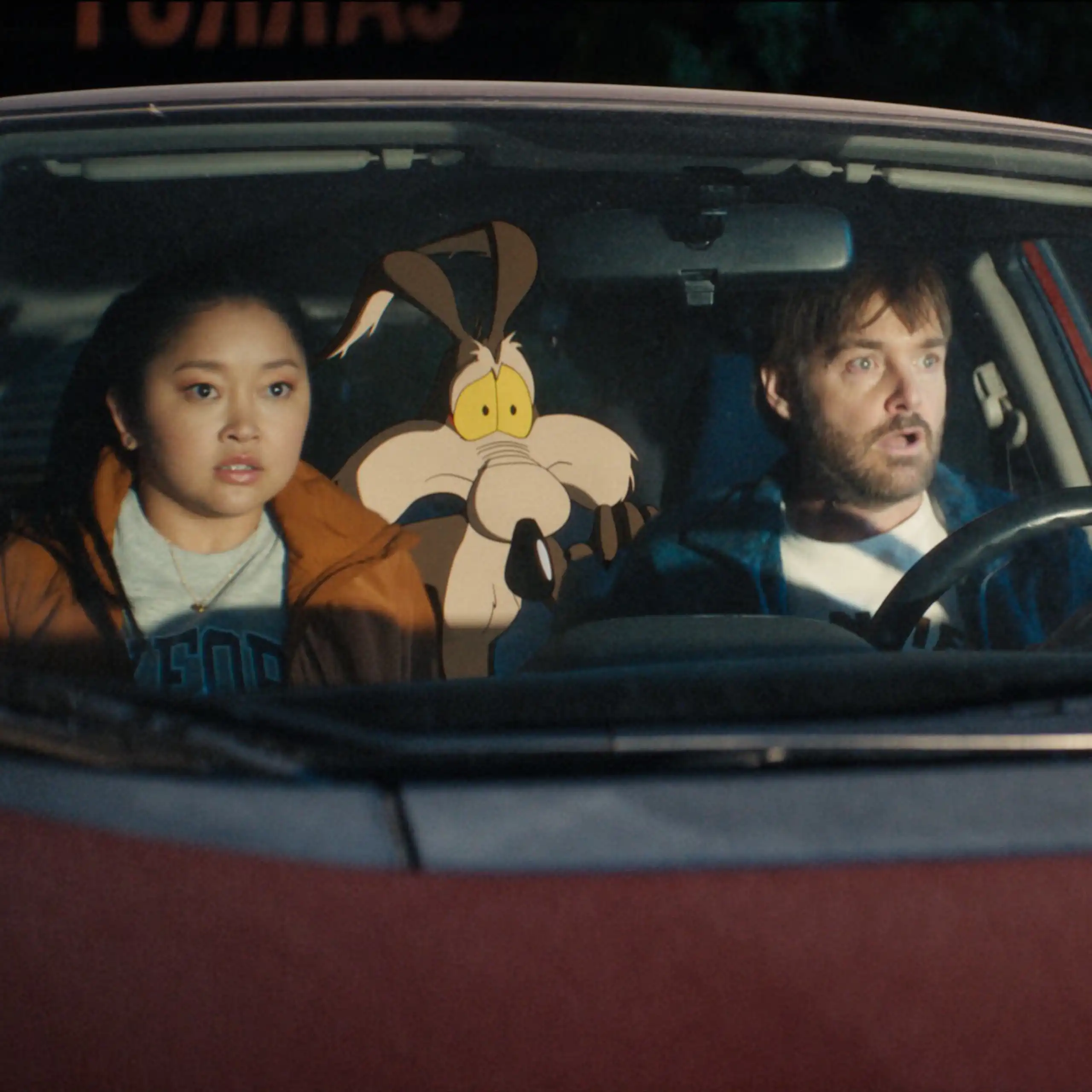 Human actors Lana Condor and Will Forte sit in a car with the animated character Wile E. Coyote in a still from the film Coyote vs. Acme