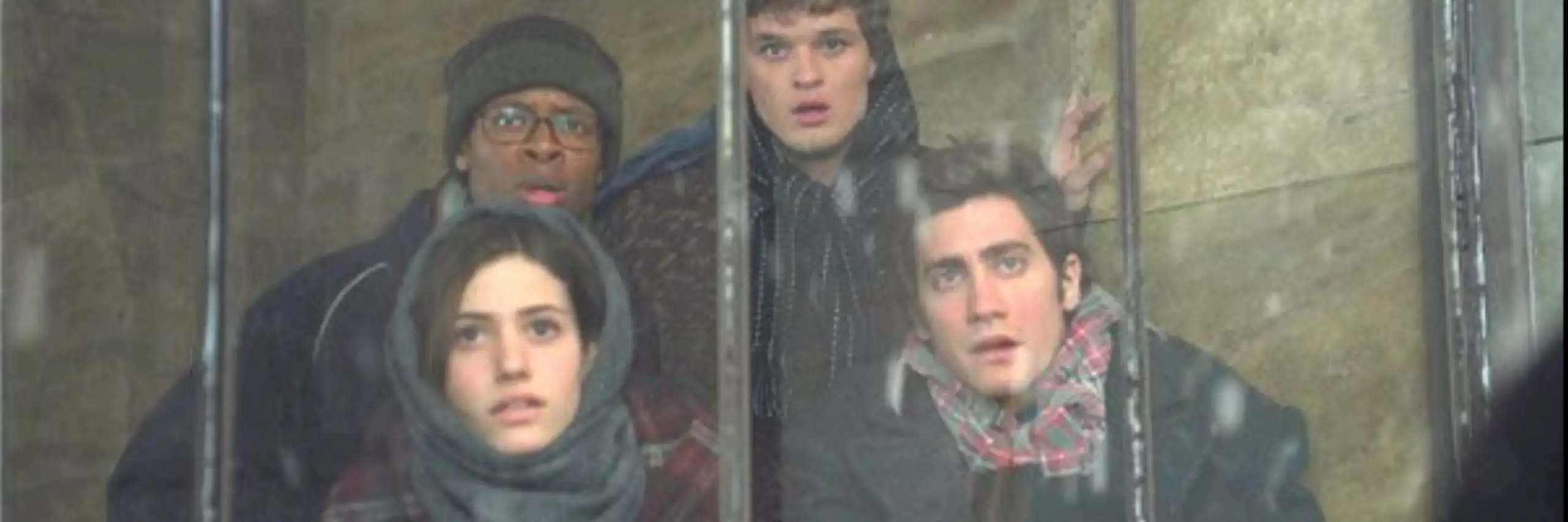 Quatre personnages du film regardent, tétanisés, à travers une baie vitrée.