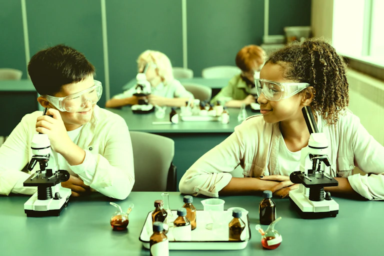 Dos niños haciendo prácticas de ciencia en un laboratorio escolar.