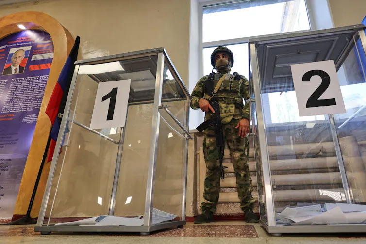 A soldier stands between two ballot boxes at an election centre in Russian-controlled Donetsk, September 19 2026.