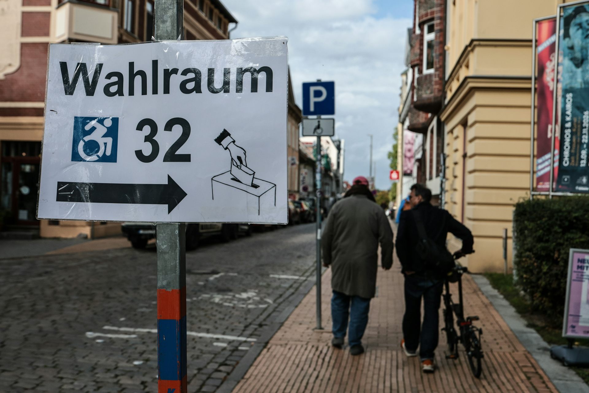 Two people walk past a polling station sign in the city of Schwerin.