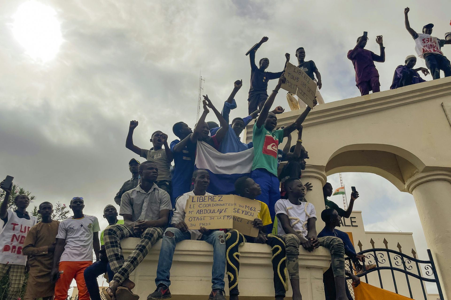 People standing on a building raise their fists in triumph.