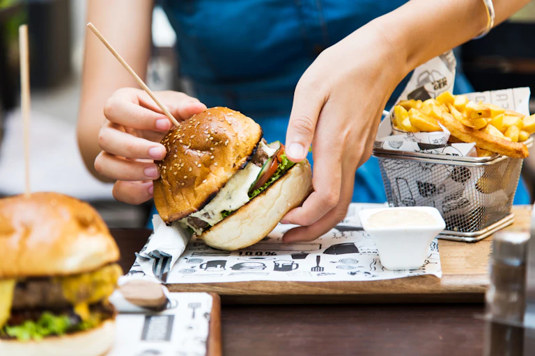 Photo d’une personne s’apprêtant à manger un hamburger.
