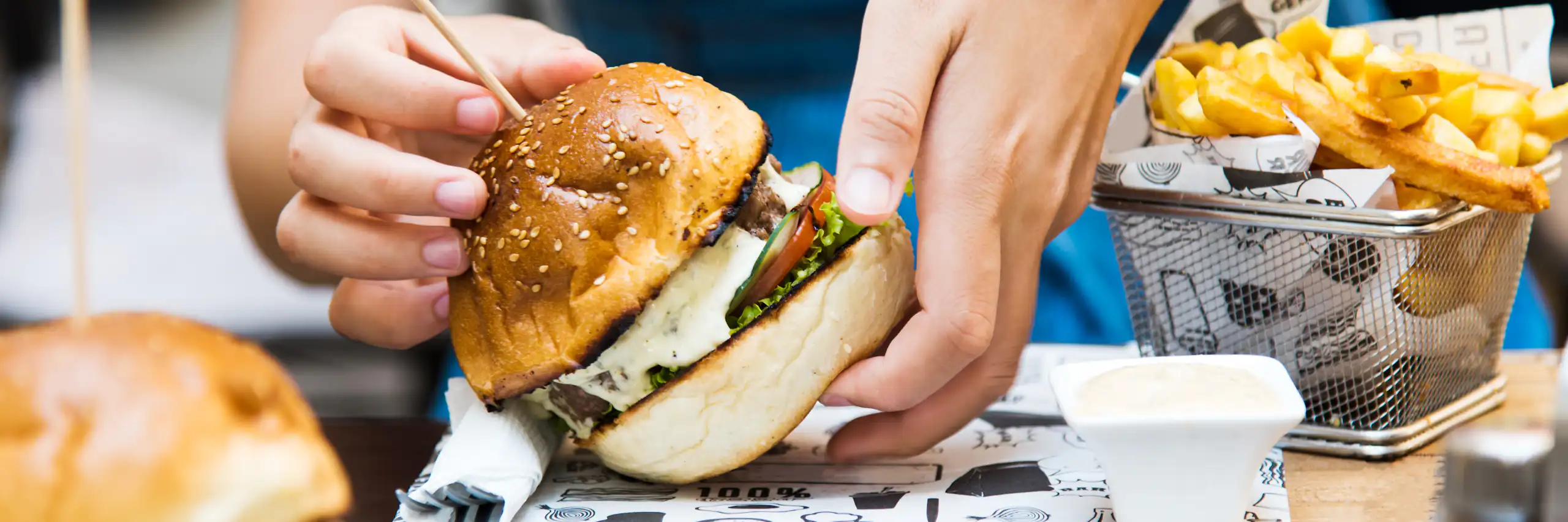 Photo d’une personne s’apprêtant à manger un hamburger.