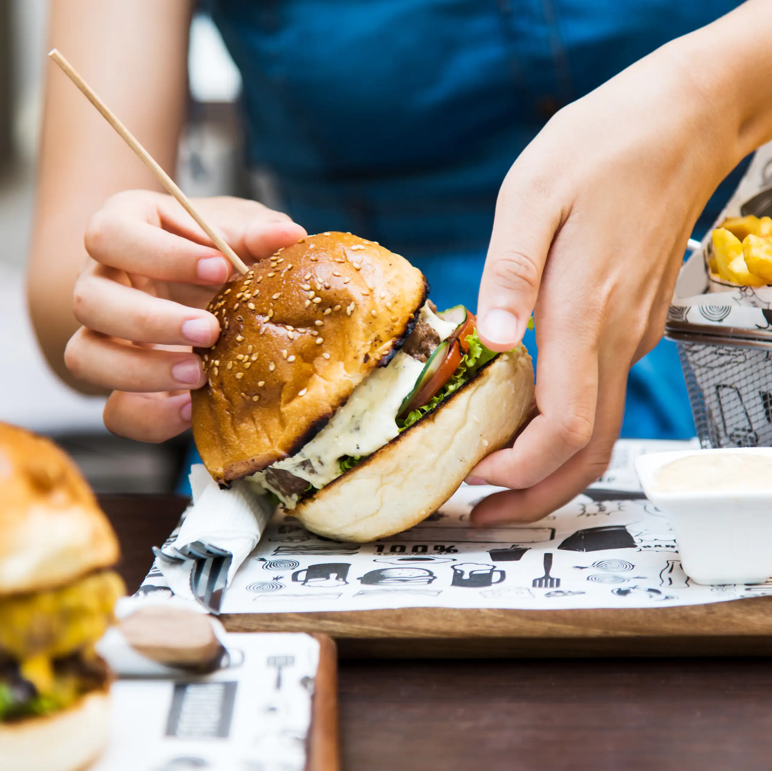 Photo d’une personne s’apprêtant à manger un hamburger.
