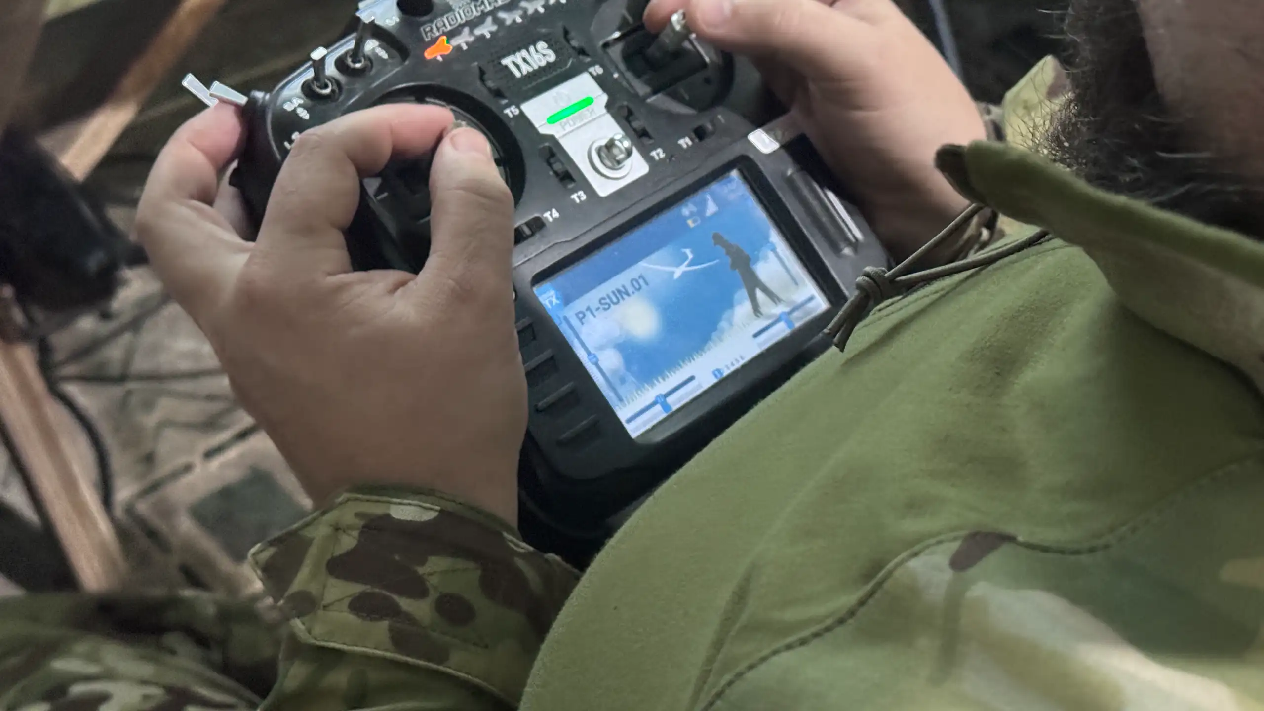 A soldier's hands are on a remote driving control.