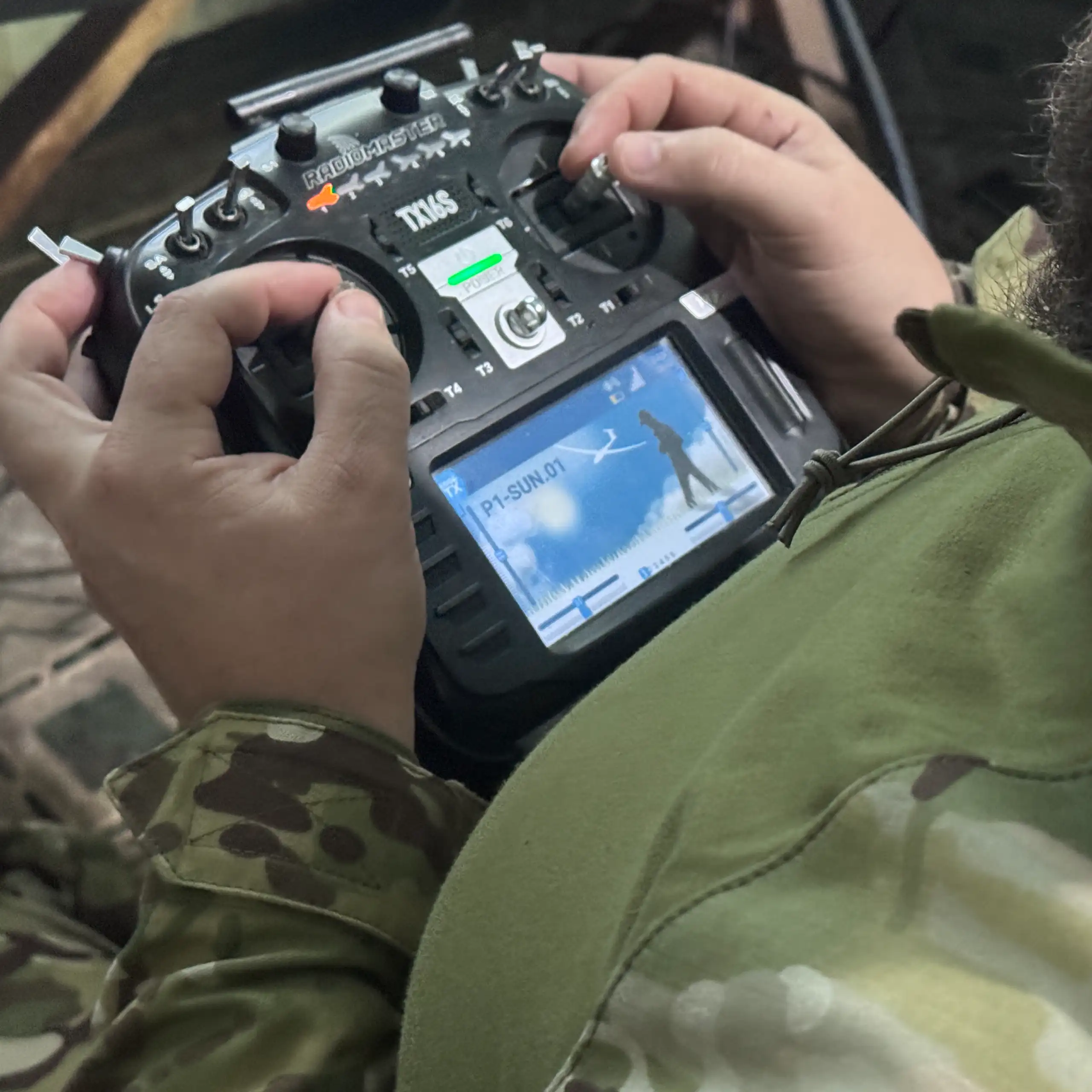A soldier's hands are on a remote driving control.