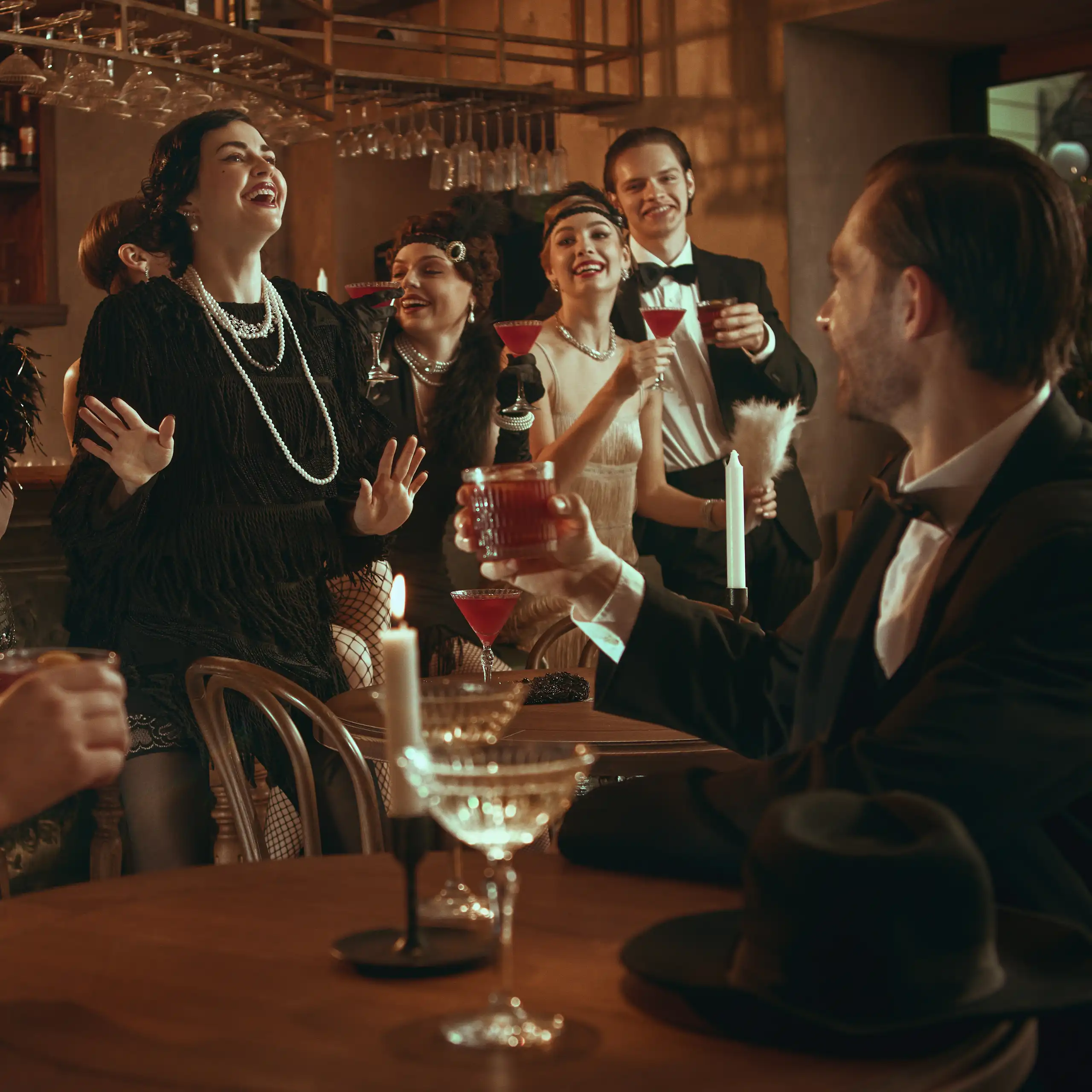 Um grupo de convidados de uma festa retrô rindo e comemorando enquanto bebem coquetéis.