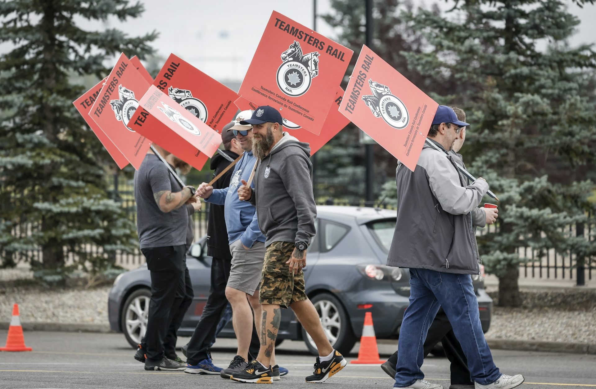People walk back and forth carrying signs that say 'Teamsters Rail'
