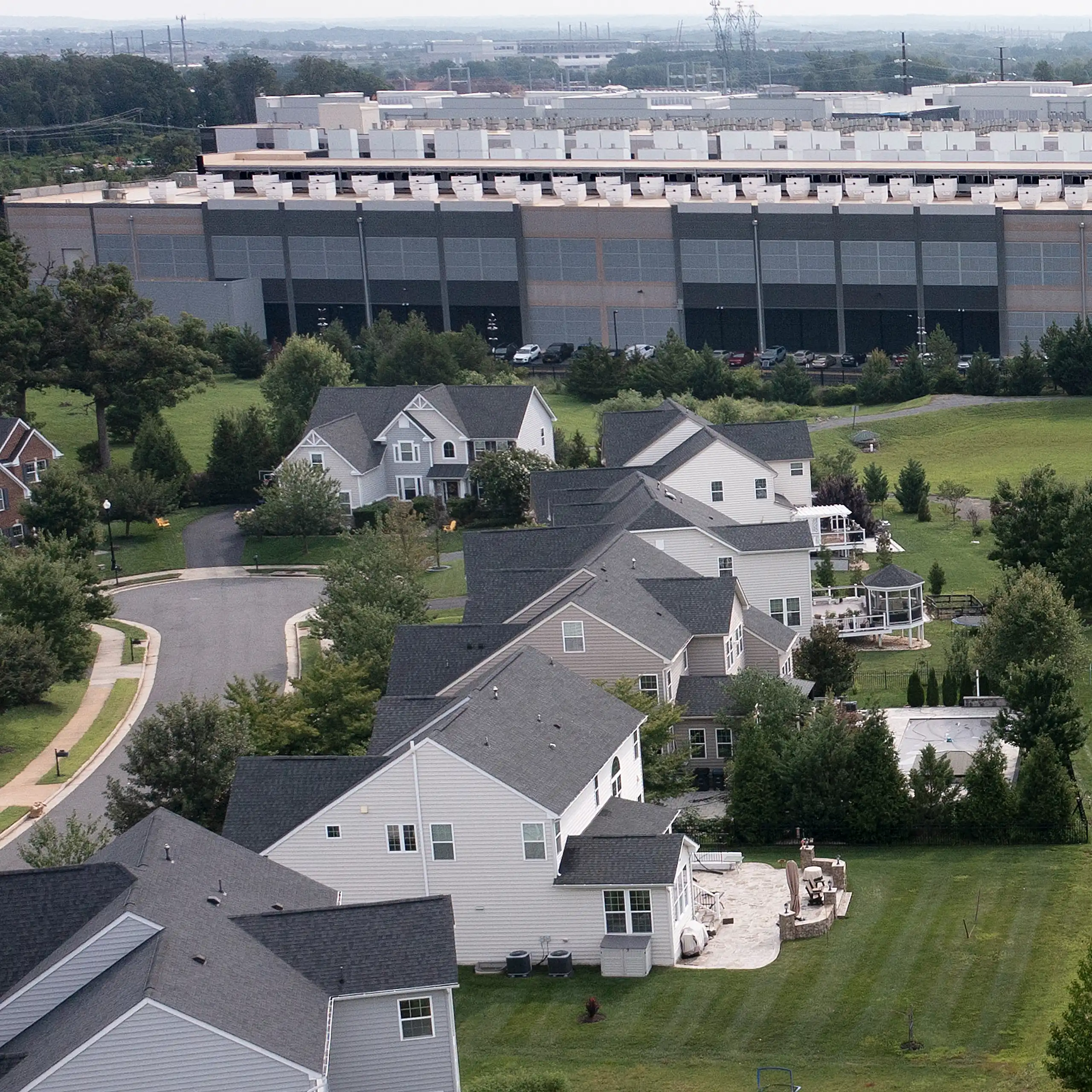 An aerial photo shows a residential neighborhood directly adjacent to a large data center building.