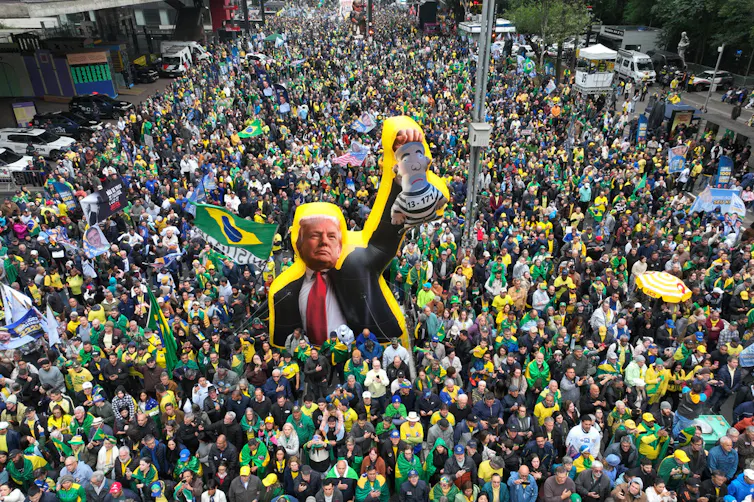 Throngs of demonstrators march with flags and a large effigy.