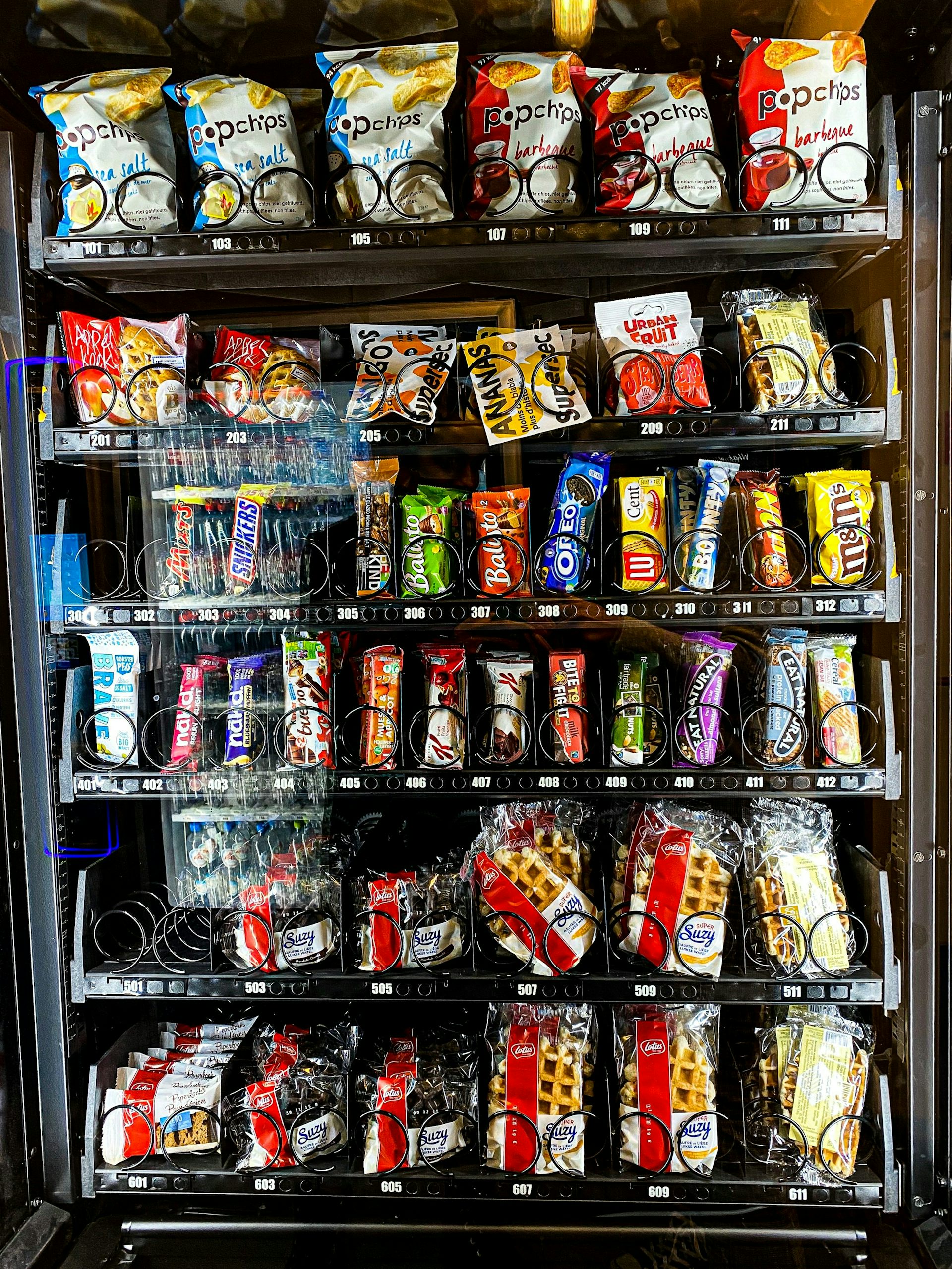 A vending machine filled with chips, chocolate bars and other packaged snacks