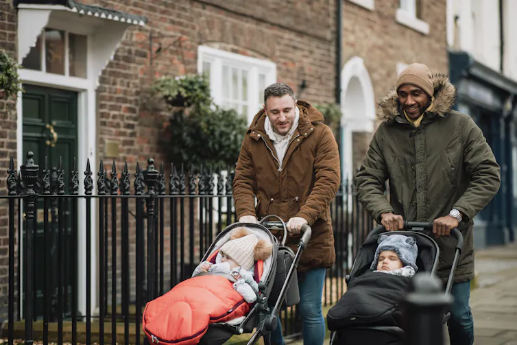 two dads walking their babies in strollers