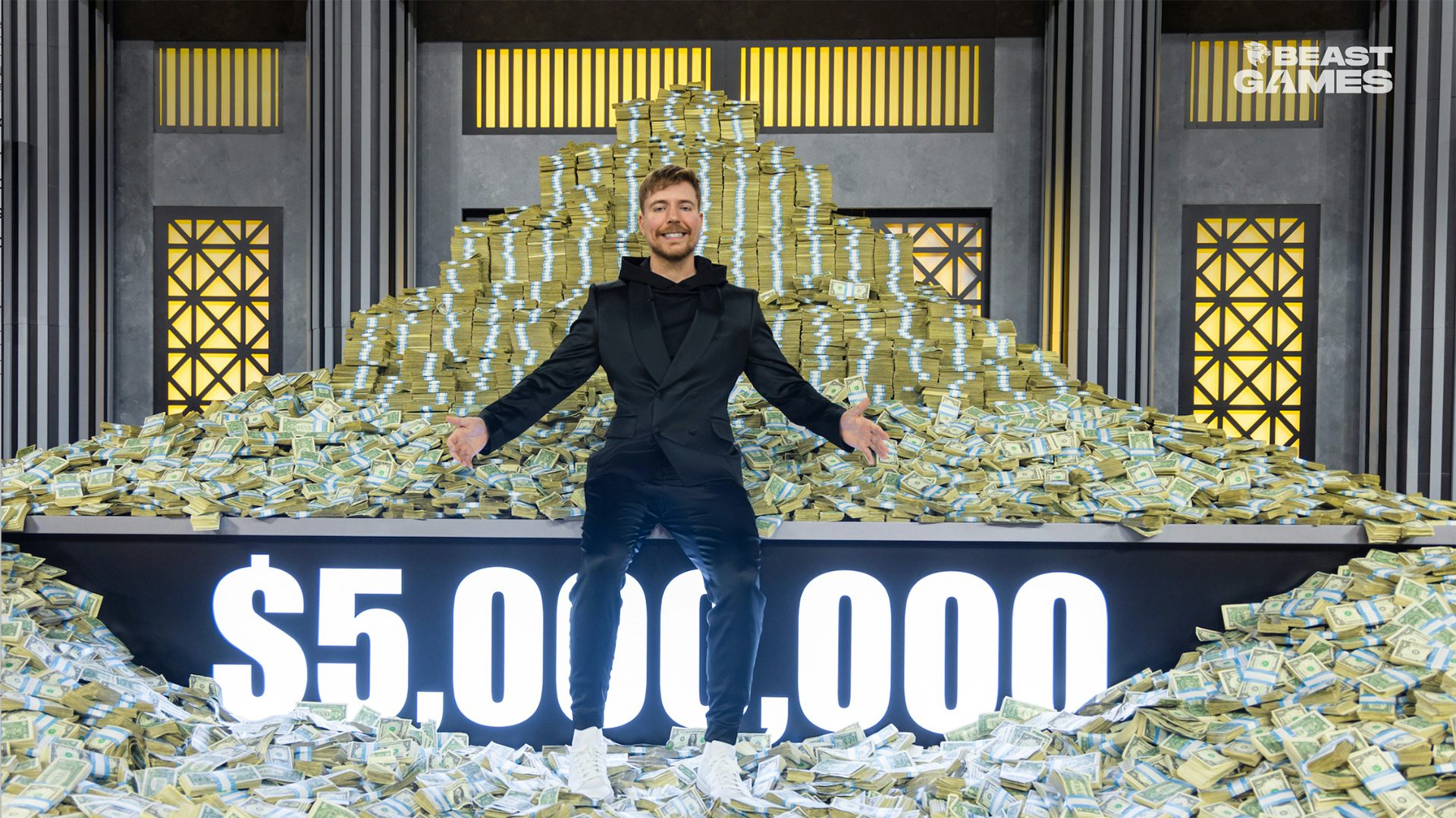 A man in a black suit sits in front of a giant piles of bash