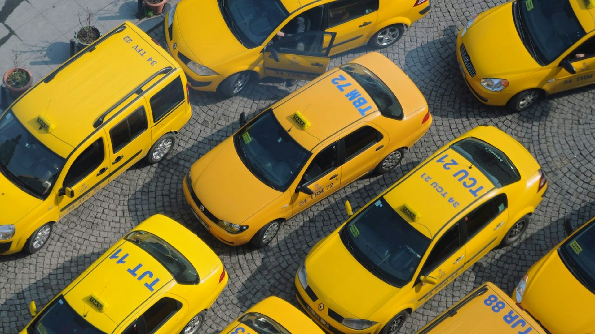 Bright yellow taxis packed closely together, appearing to be stuck in traffic.