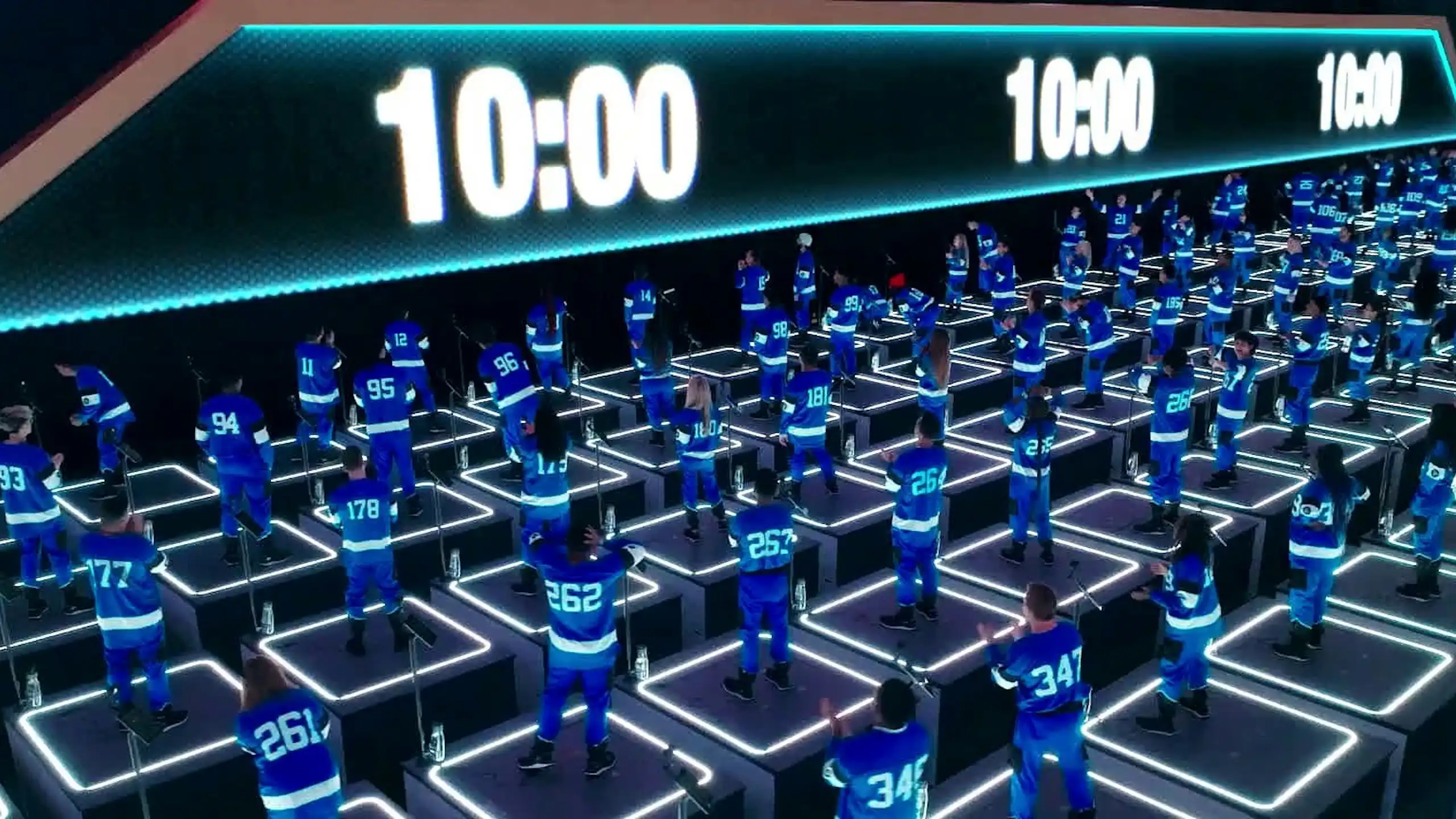 People in blue jumpsuits stand on platforms as they watch a countdown