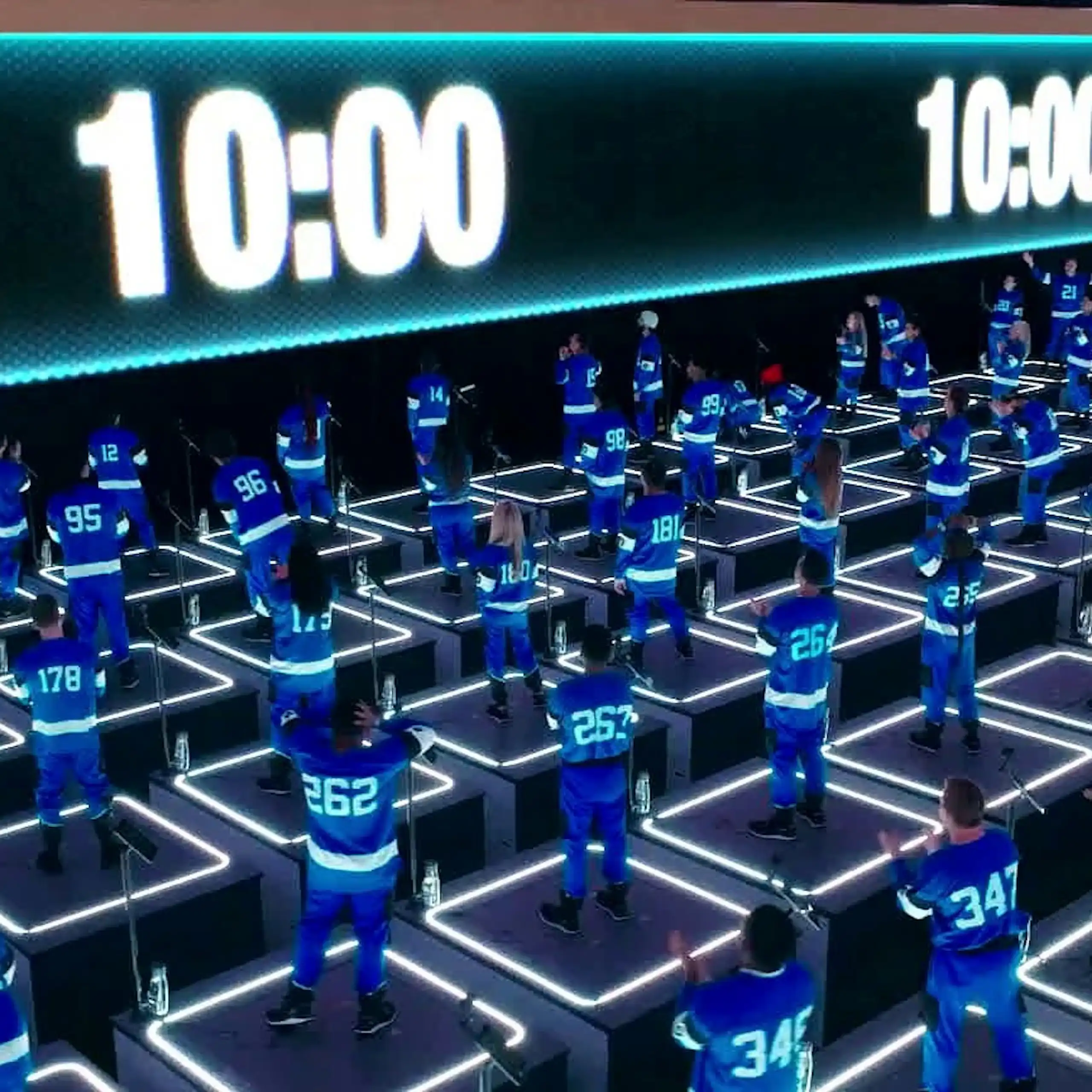 People in blue jumpsuits stand on platforms as they watch a countdown