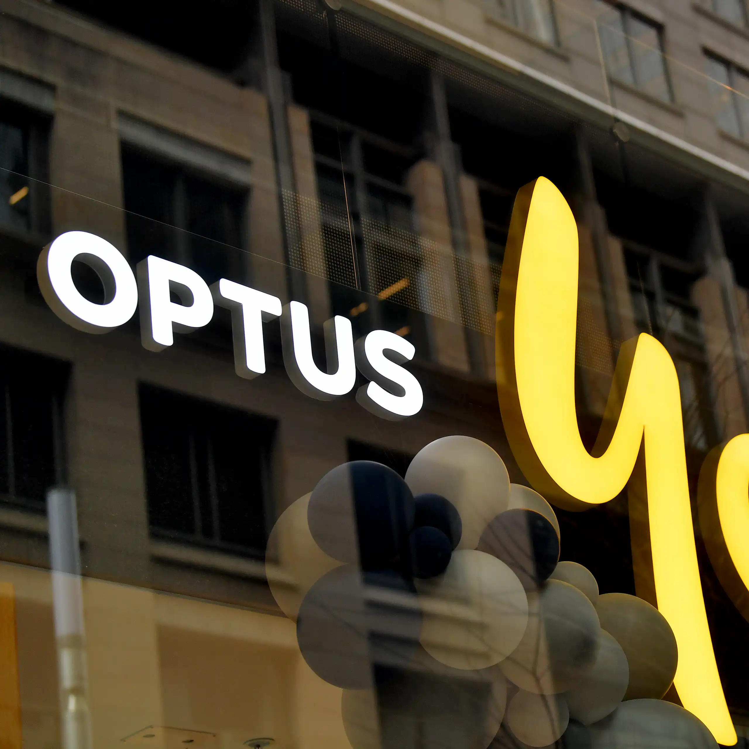 A shopfront with a yellow and white sign that reads "Optus yes".