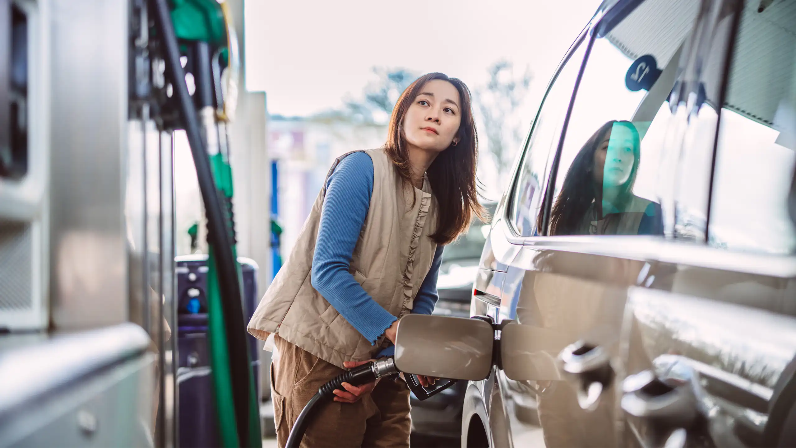 A woman puts fuel into her car at a petrol station