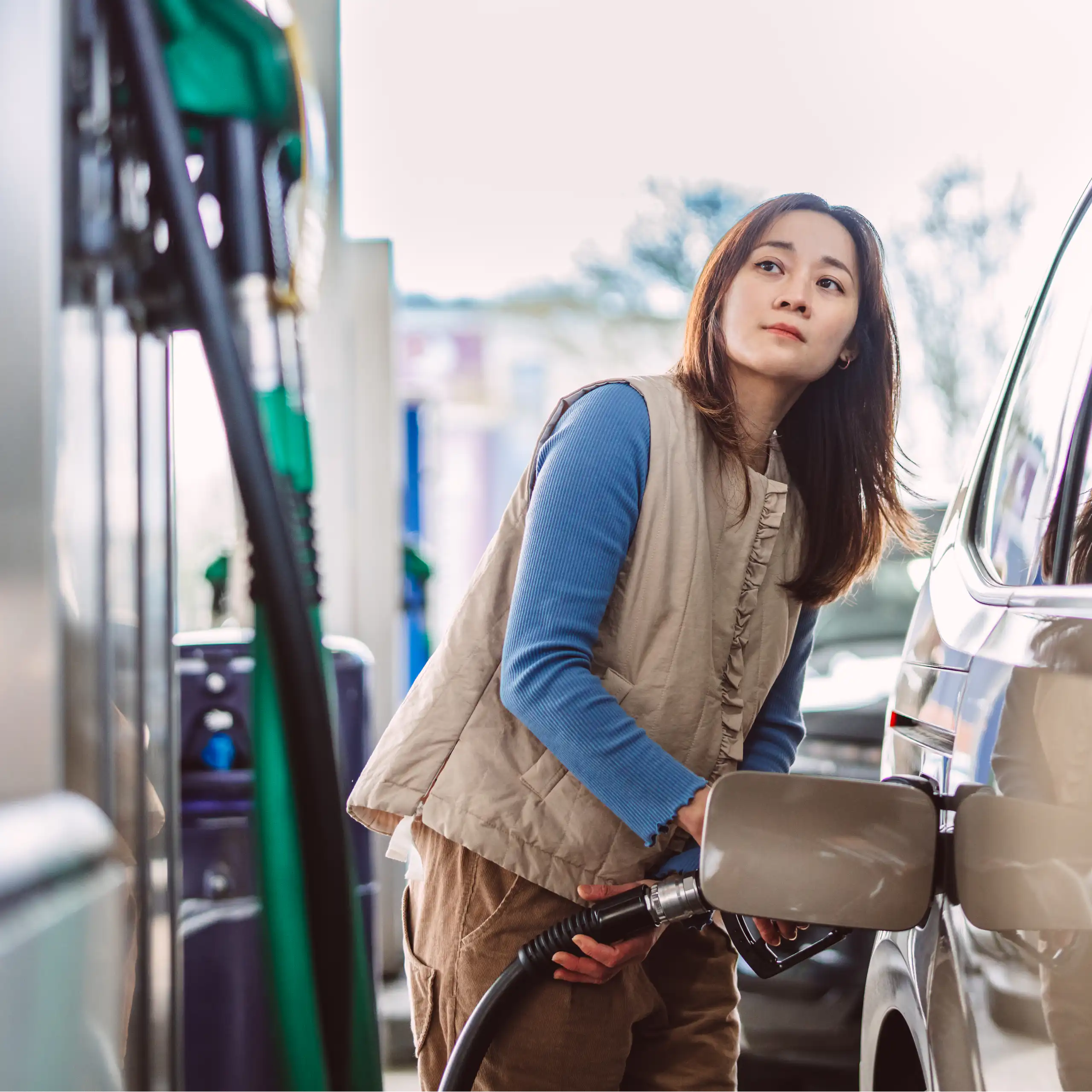 A woman puts fuel into her car at a petrol station
