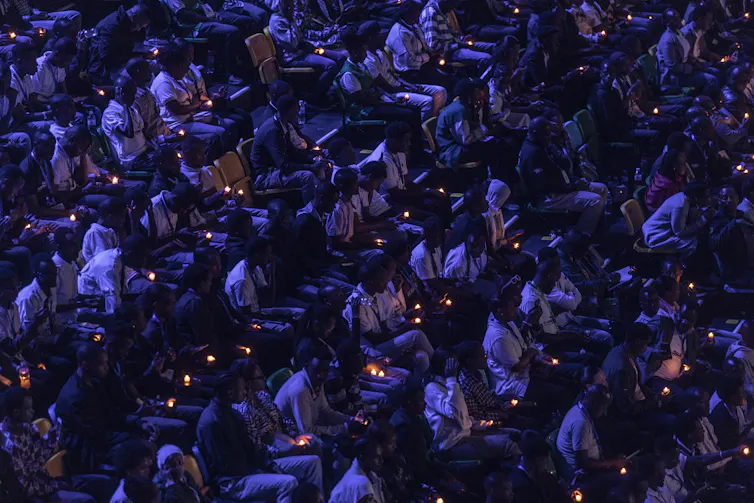 People dressed in white hold candles during a night vigil.