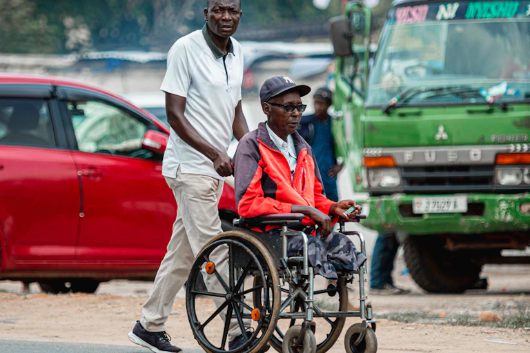 Man pushing an elderly person in a wheelchair
