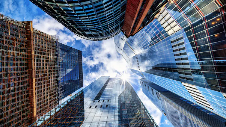 Looking up to sky past tall shiny buildings.