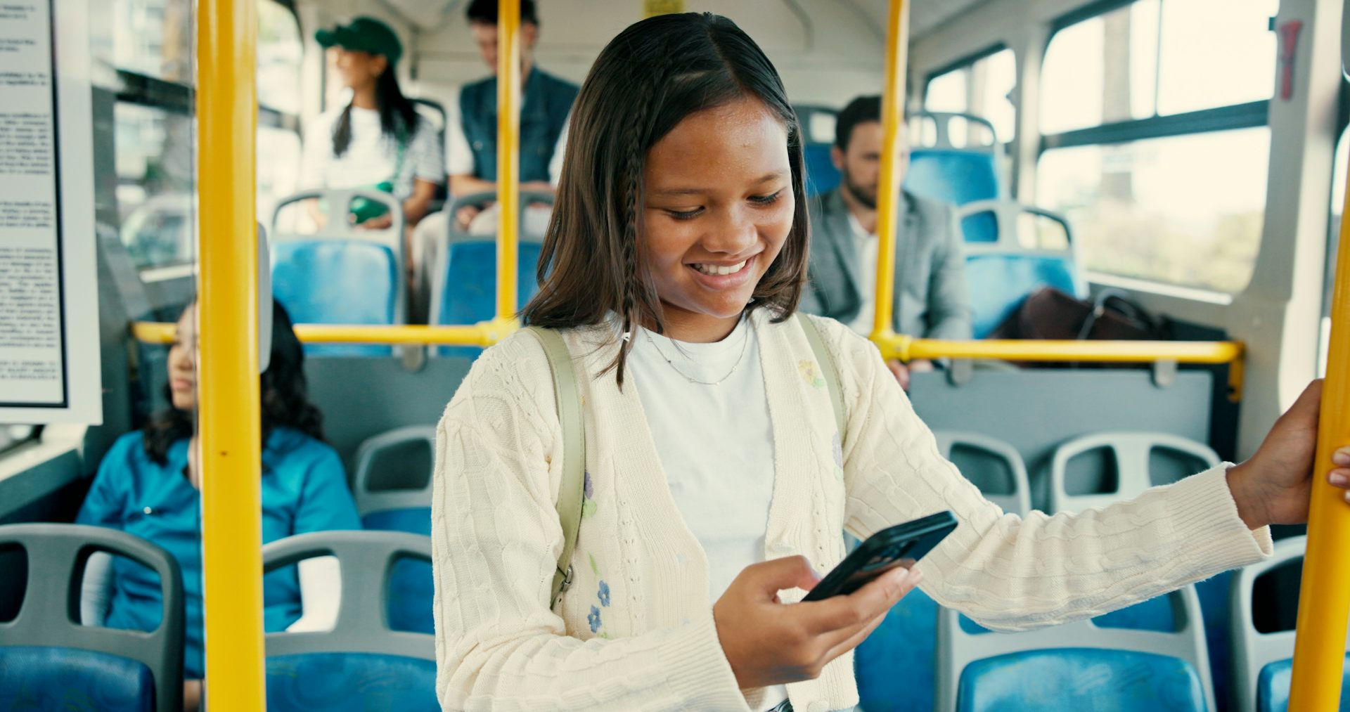 Young girl on bus smiling at her phone
