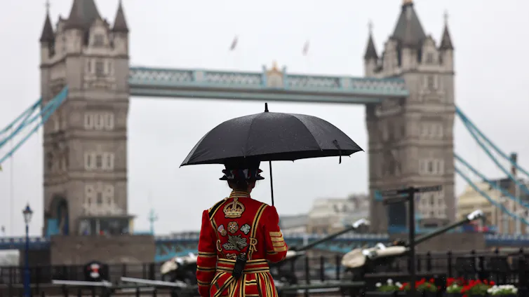 Beefeater under umbrella with Tower Bridge in background