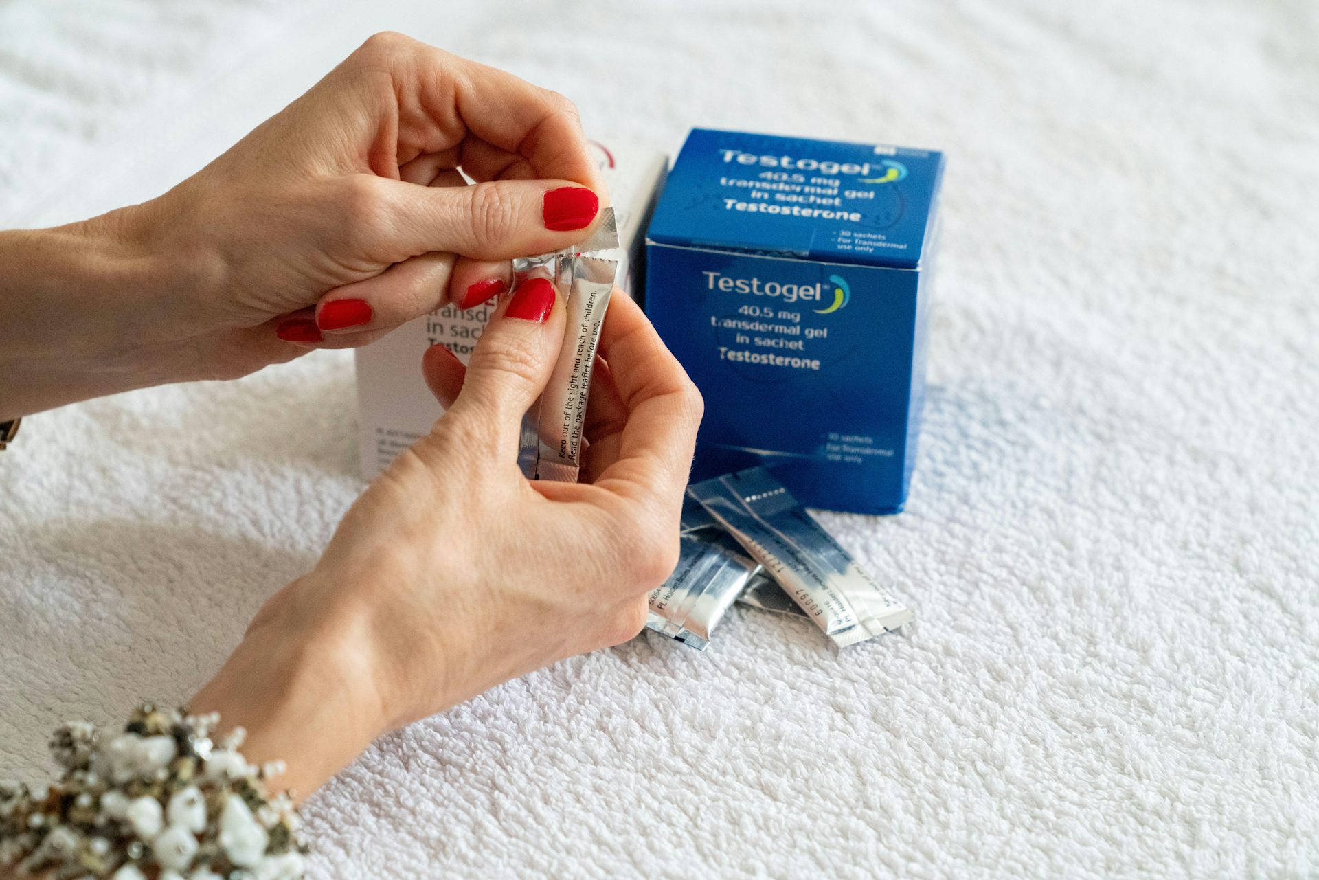 A woman's hands opening a testosterone gel product.