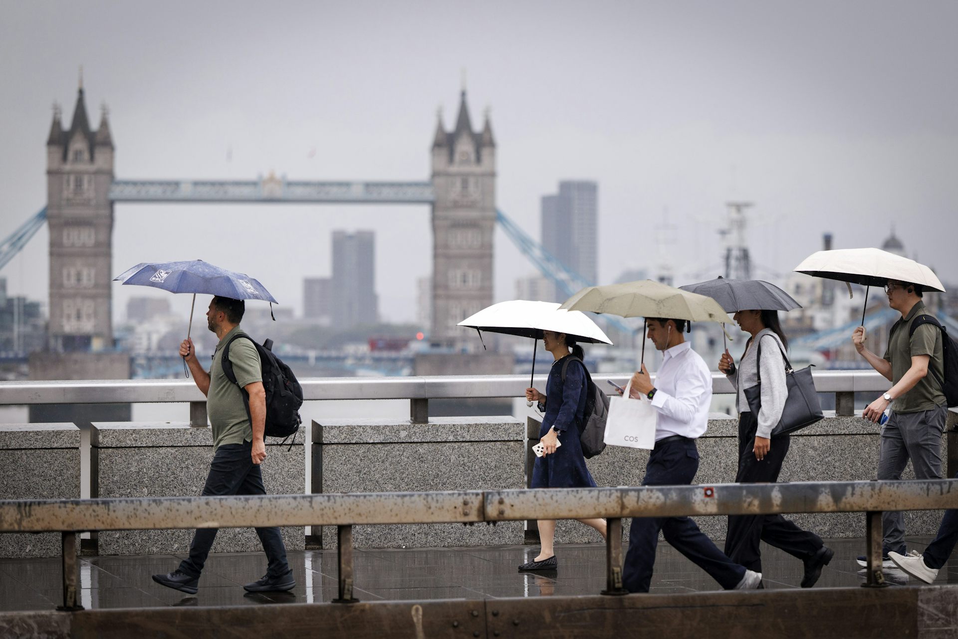 People with umbrellas on grey day, Tower Bridge in background