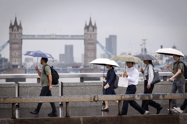People with umbrellas on grey day, Tower Bridge in background