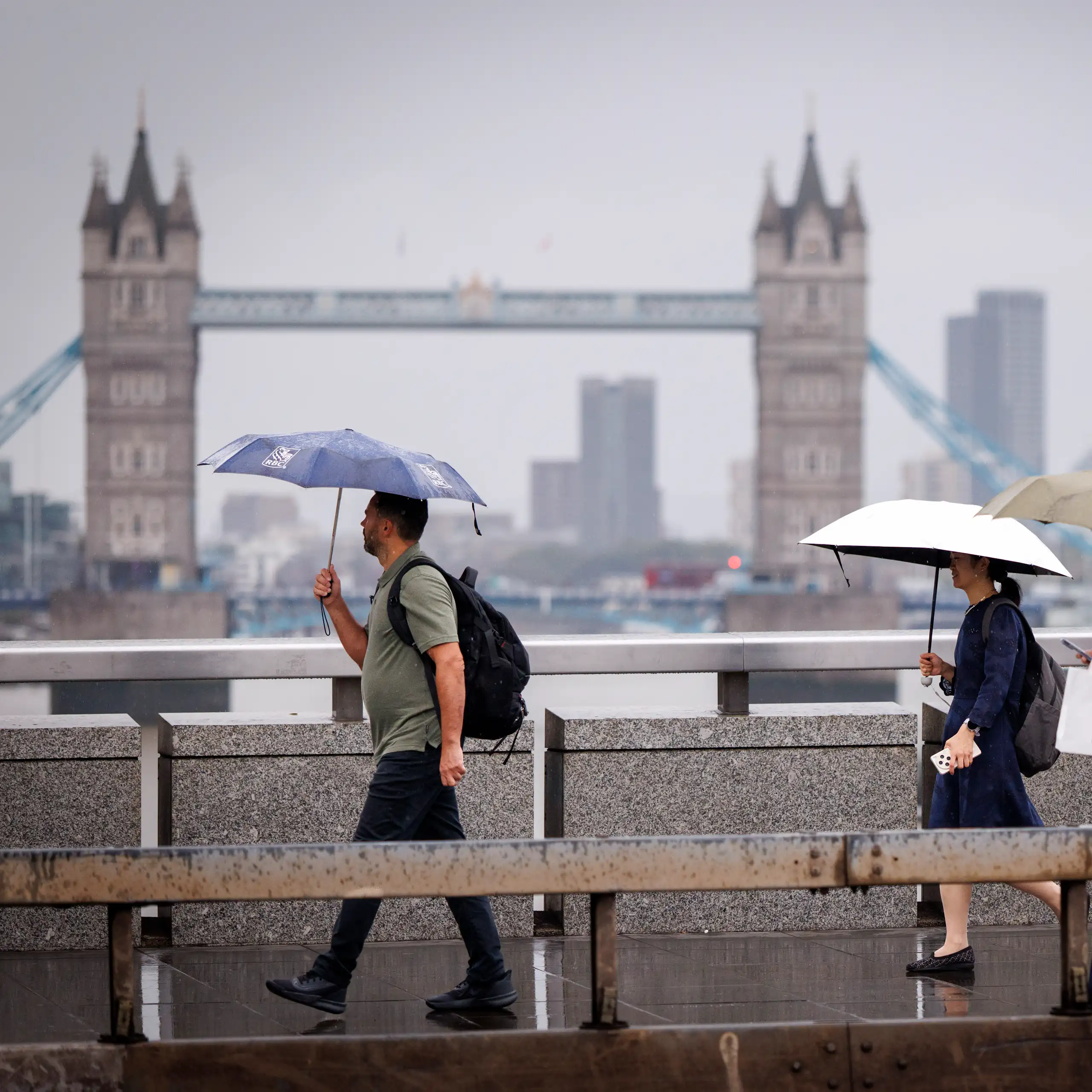 People with umbrellas on grey day, Tower Bridge in background