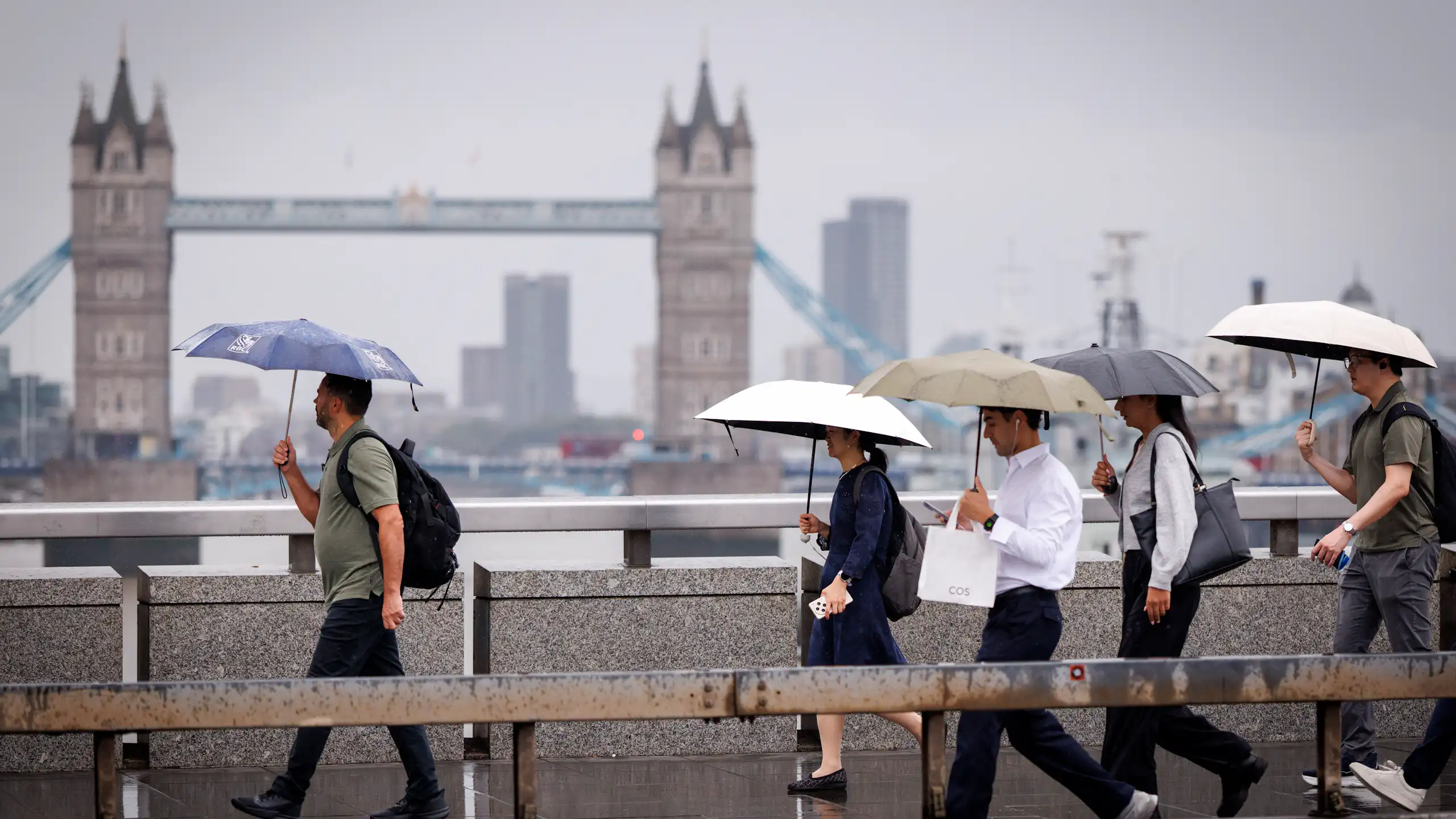 People with umbrellas on grey day, Tower Bridge in background