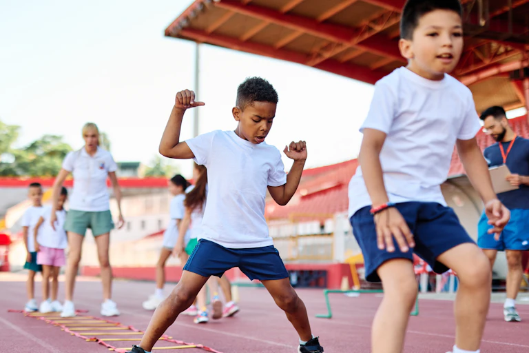 De jeunes enfants font du sport dans un stade.