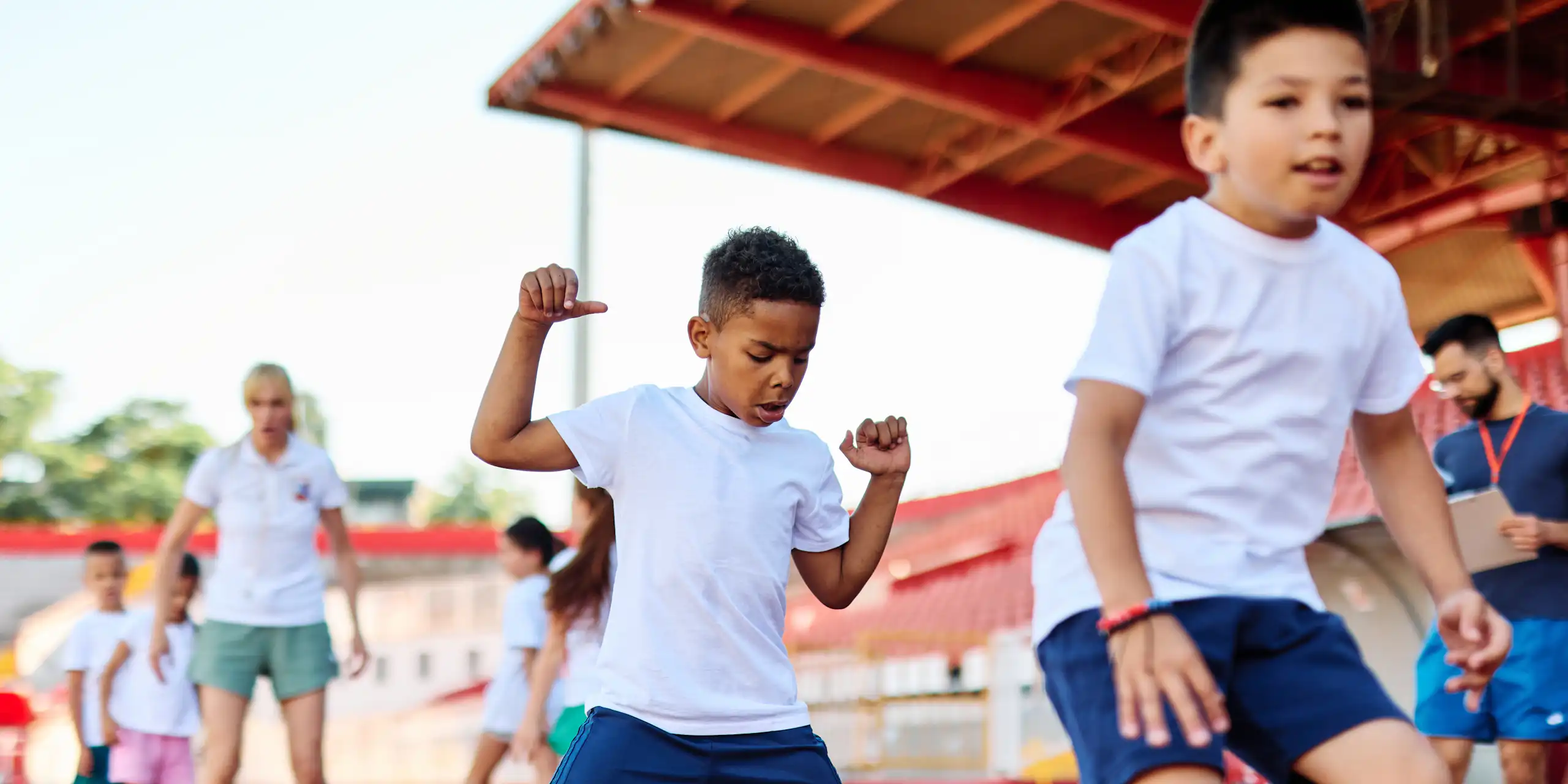 De jeunes enfants font du sport dans un stade.