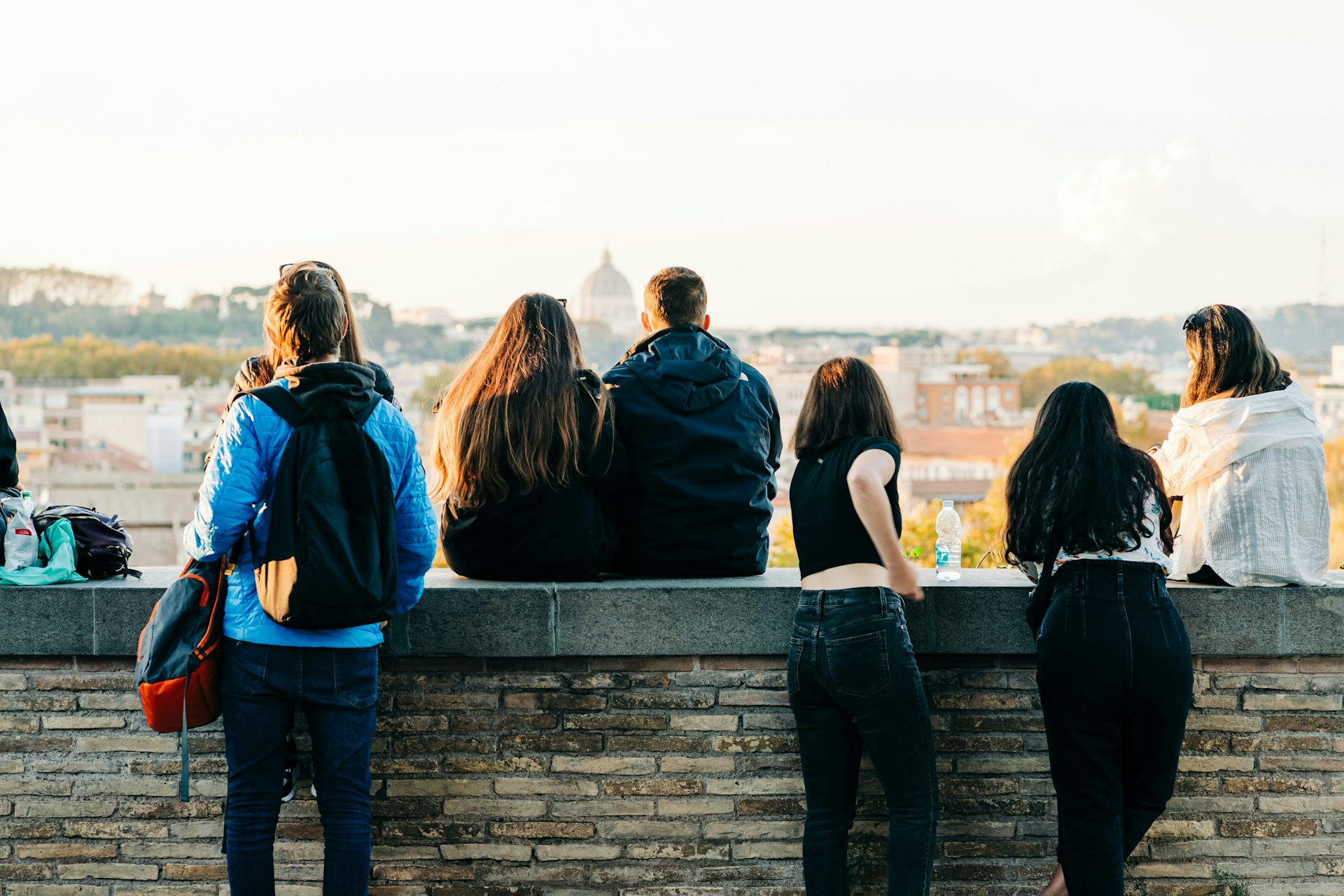young people sit on a stone wall in a european city