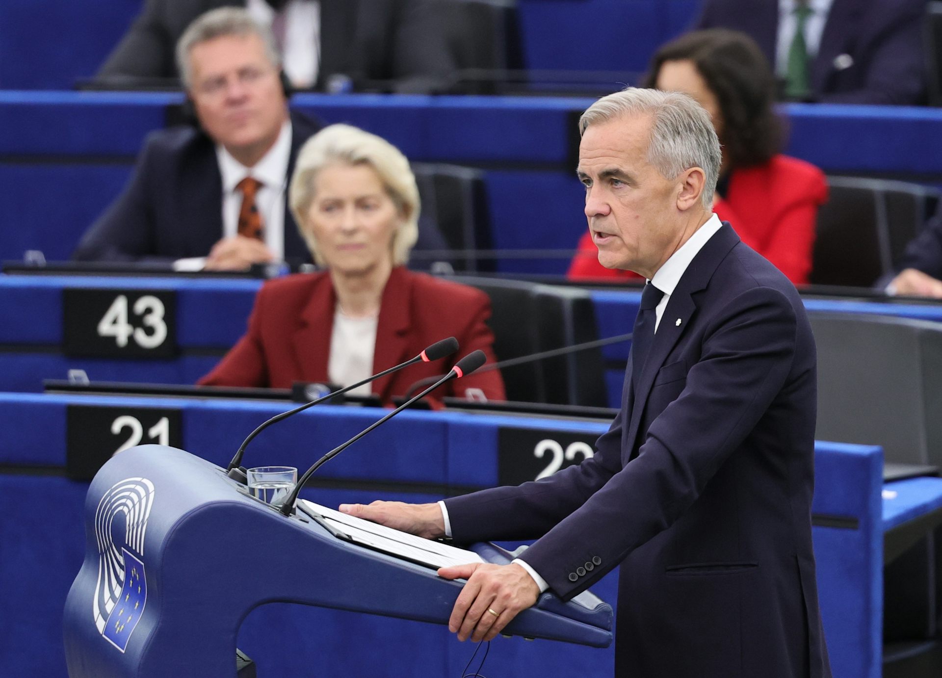 Canada's prime minister, Mark Carney, speaks at a podium watched by EUropean commission president, Ursula von der Leyen.