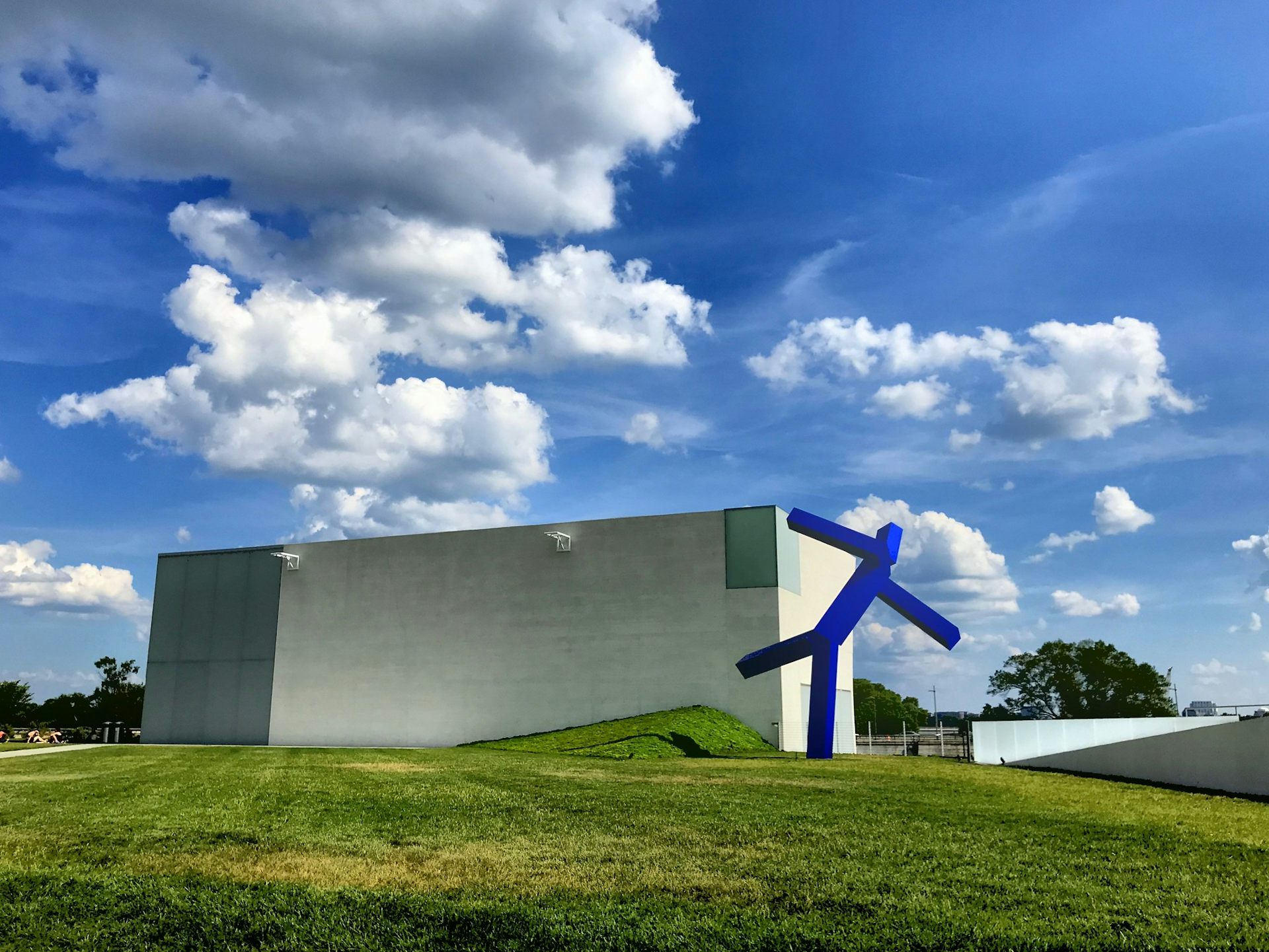 An abstract geometric blue sculpture on a lawn.