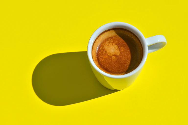 Xícara de café contra um fundo amarelo brilhante