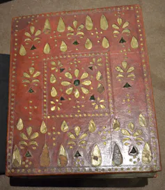 The front and back boards, covered with openwork red leather, lined with gold foil and velvet.