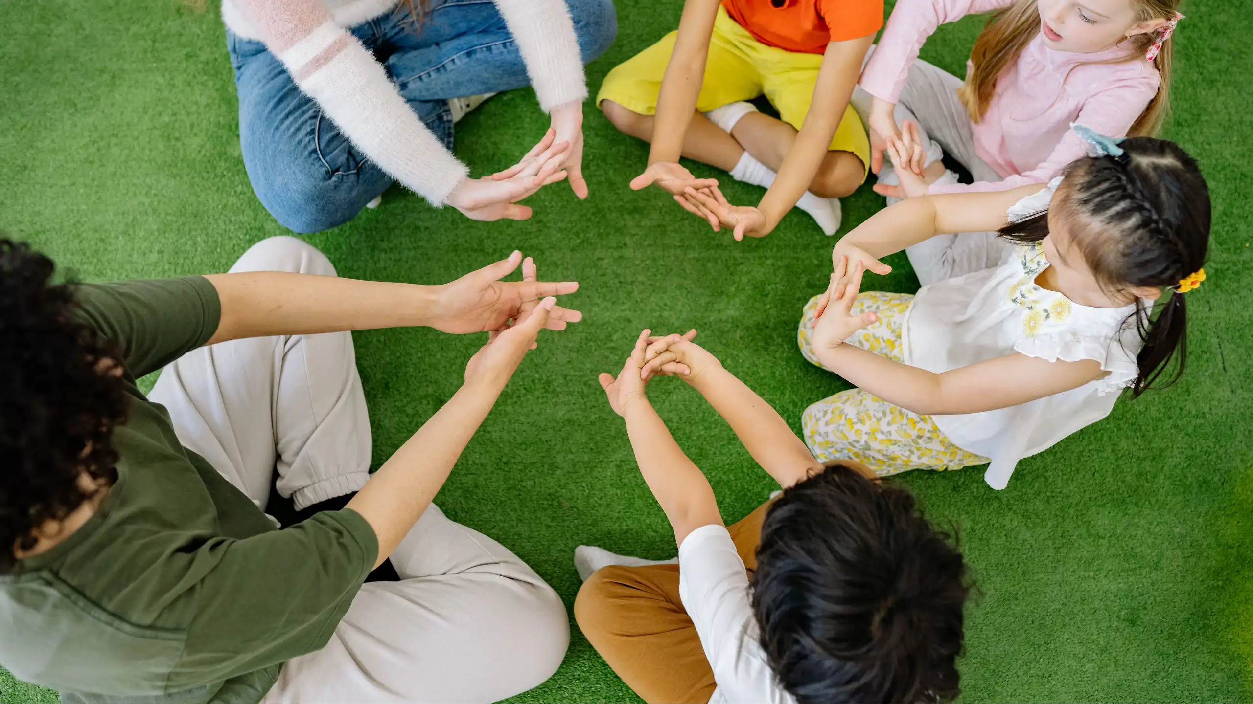 Children sitting in a circle, all making a hand pattern.