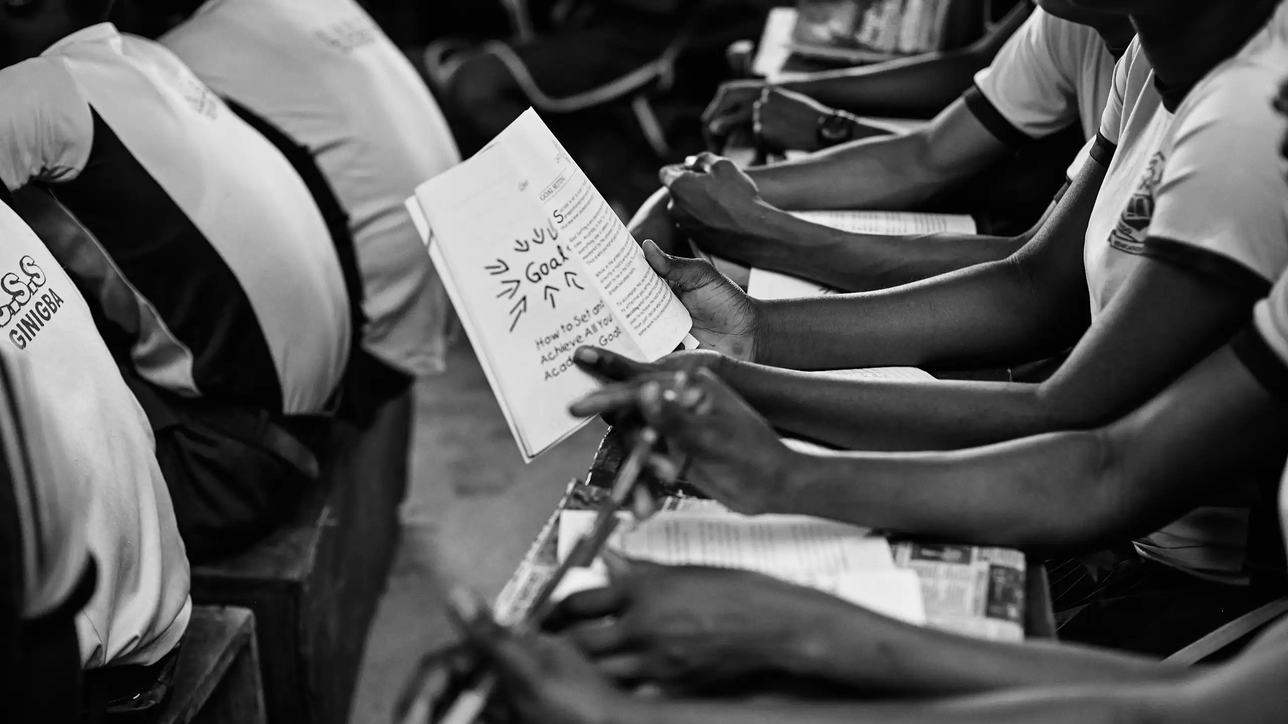 A group of school children hold books.