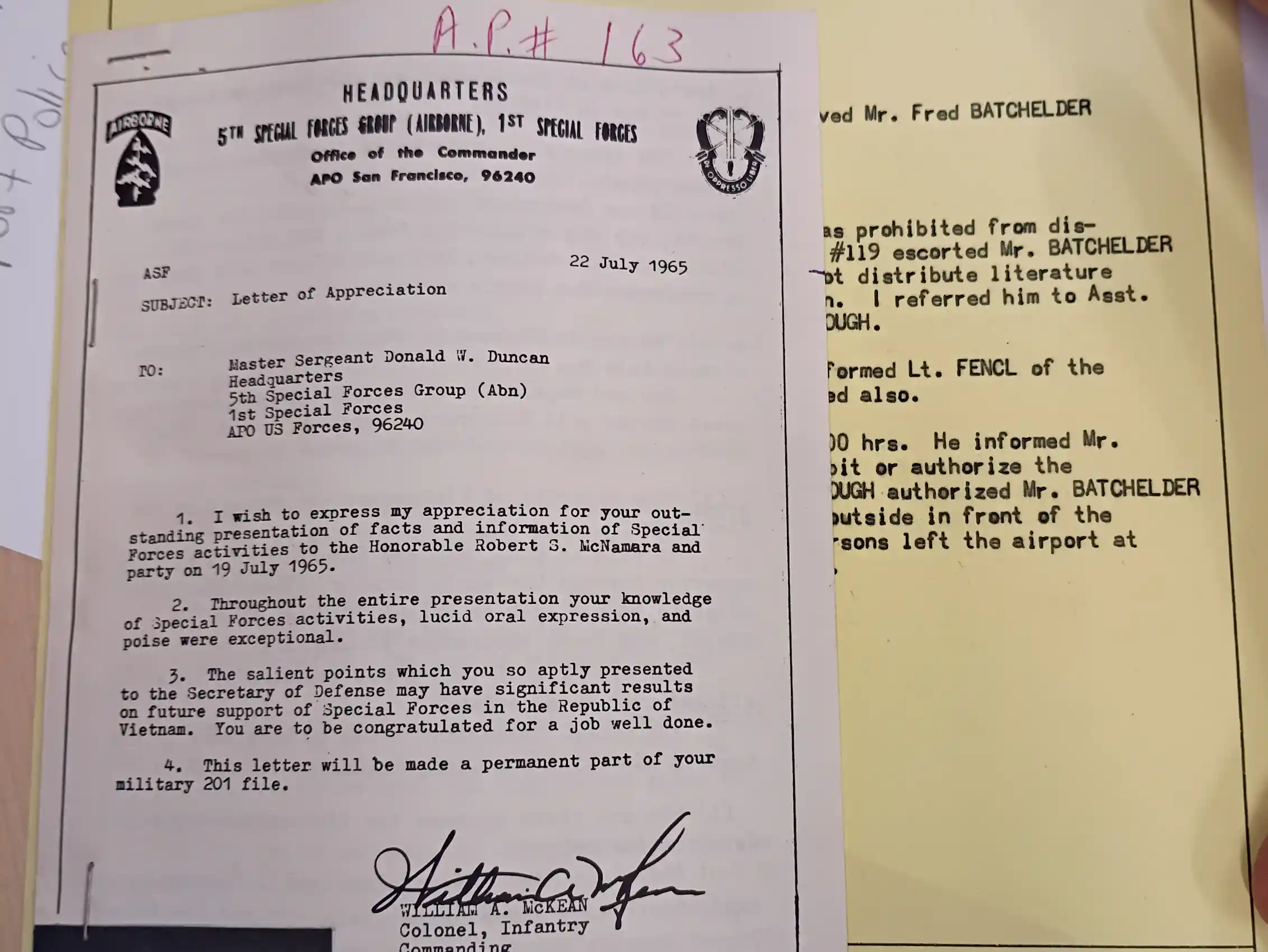 A yellow paper with typewritten notes and a white paper that says
